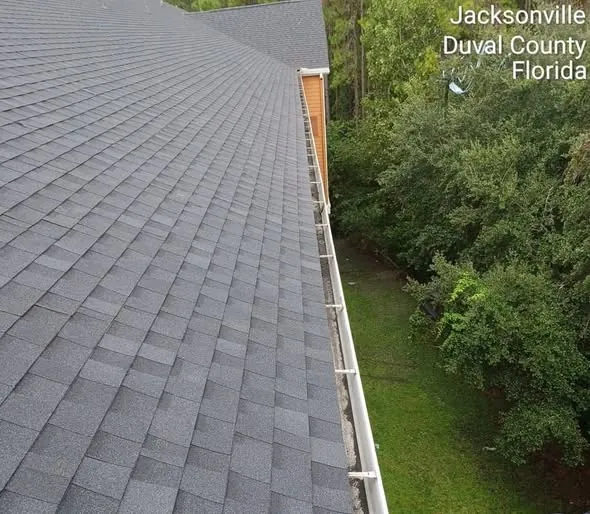 Shingle roof edge with newly installed seamless gutter and drip edge